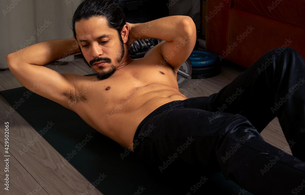 Young latin shirtless man exercising at home, doing abs. Young latin shirtless man exercising at home, doing abs.