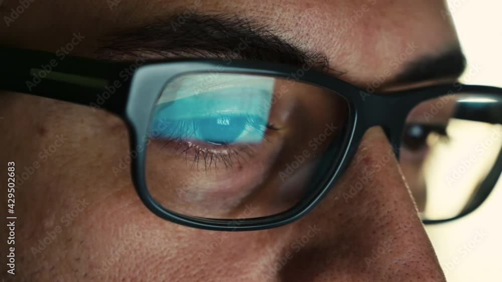 Macro on the eye of a software engineer who is working: the gaze focused on the screen,on the lens of the glasses we see the reflection.Clear and crystal clear image on the right lens. Selective focus Macro on the eye of a software engineer who is working: the gaze focused on the screen,on the lens of the glasses we see the reflection.Clear and crystal clear image on the right lens. Selective focus