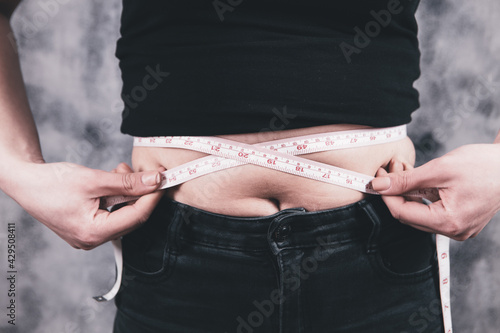 girl measures belly with a centimeter