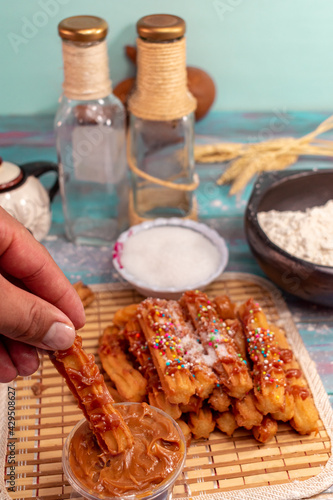 man's hand spreading arequipe to typical Spanish churros covered with colored sparks