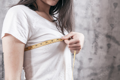 Принти на полотні Slim woman measures her breast with a measuring tape