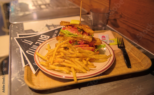 A gourmet toasted BLT sandwich with shoestring french fries on a table in a restaurant