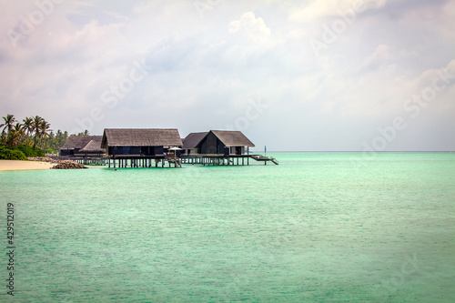 Maldivian Water Bungalows set in the sea green waters of the lagoon.
