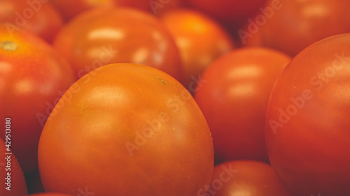 Bright red cherry tomatoes packed together in a cardboard box,  makes it look like a sea of red balls. Food processing and shipment concept photo.
 photo