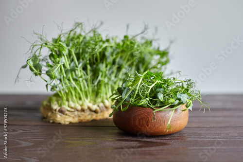 Pea microgreens on wooden table. Bowl with cutted micro greens pea sprouts with fresh leaves
