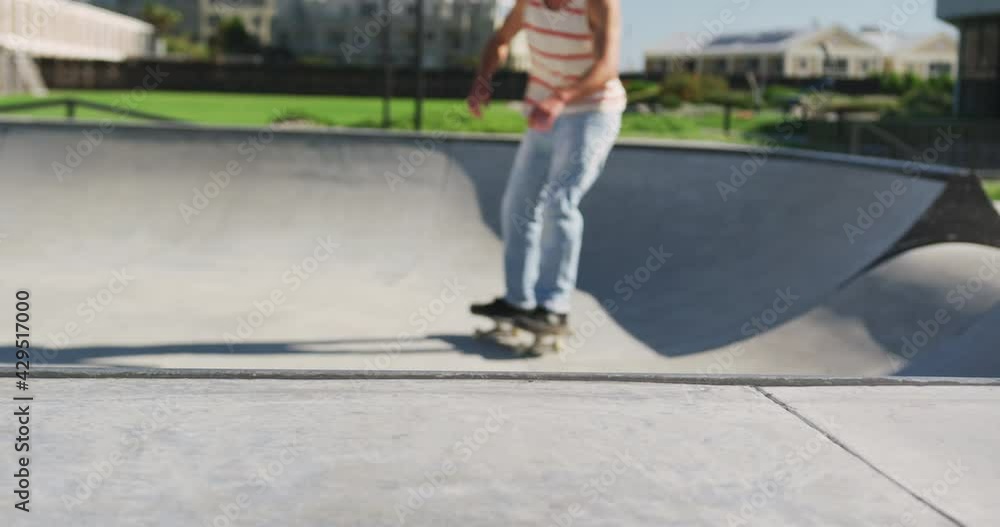 Caucasian man riding and jumping on skateboard on sunny day Caucasian man riding and jumping on skateboard on sunny day