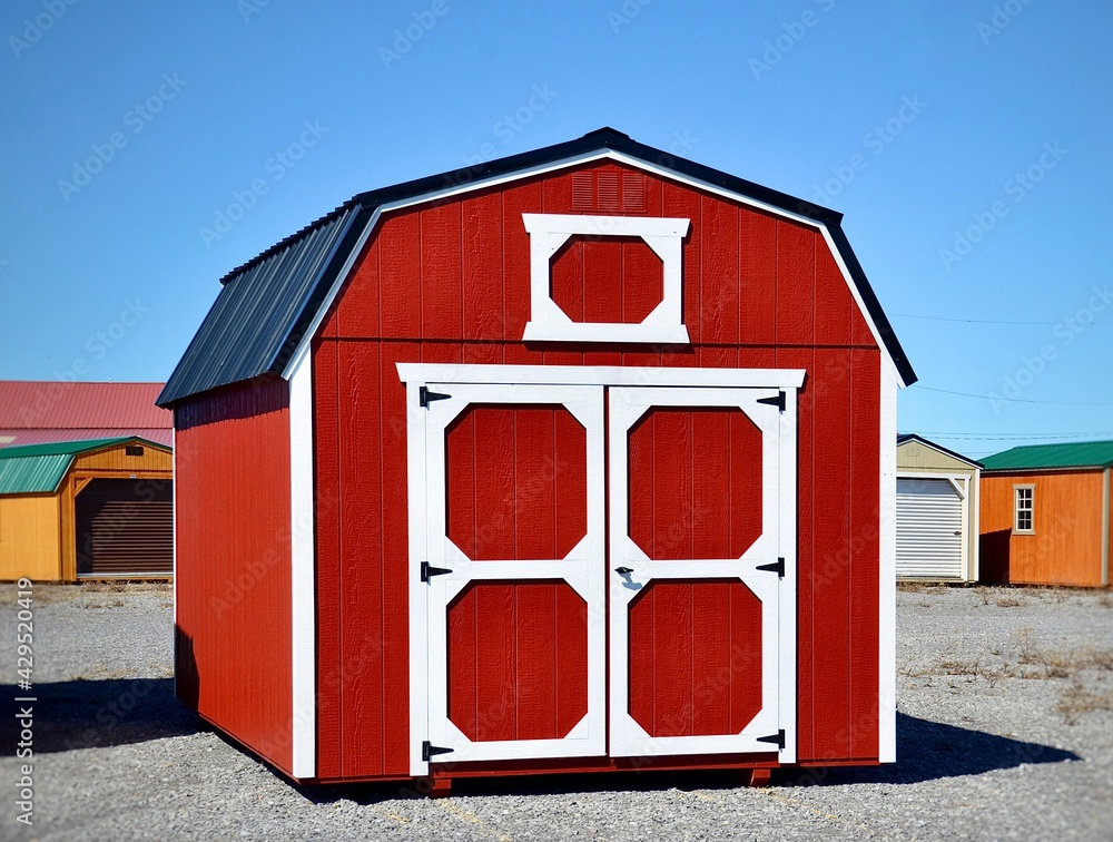 Red wooden shed. American shed is typically a simple, single-story roofed structure in a back garden or on an allotment that is used for storage, hobbies, or as a workshop.	 - obrazy, fototapety, plakaty 