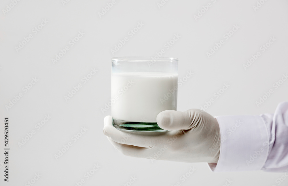 hands with glove holding glass of milk, white background hands with glove holding glass of milk, white background