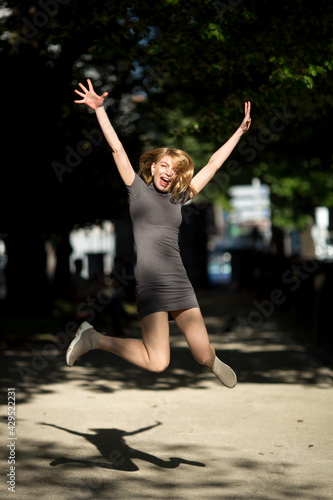 Young attractive woman in a joyous jump in the summer garden.
