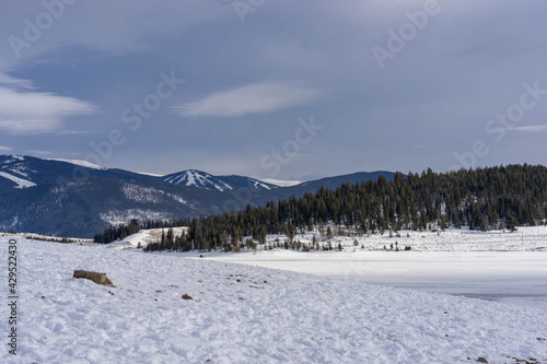 View of ski slopes on mountains behind frozen LakeDillon Colorado on partly cloudy winter day