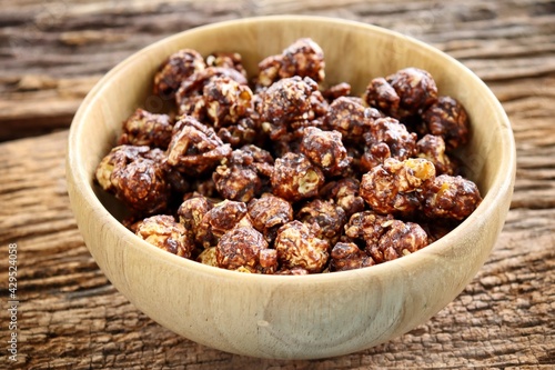 Chocolate covered popcorn on wood bowl on brown table