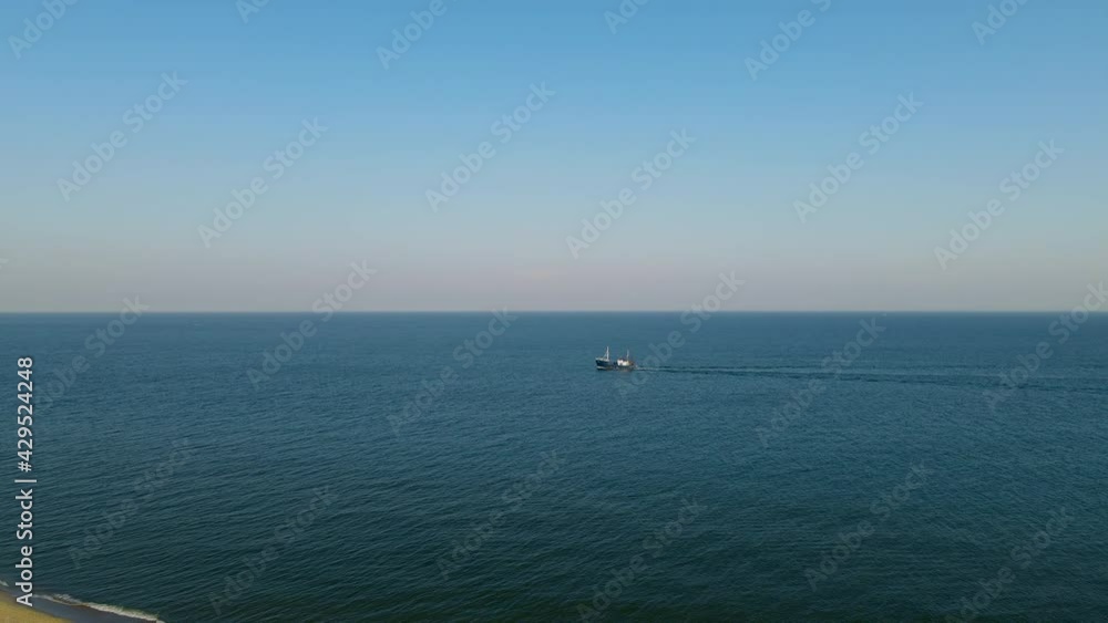 Lonely cutter sailing on calm Baltic sea close to shore, clear sky and low waves, aerial Hel, Poland Lonely cutter sailing on calm Baltic sea close to shore, clear sky and low waves, aerial Hel, Poland