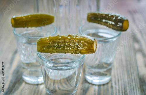 Vodka in a glass and pickled cucumber photo