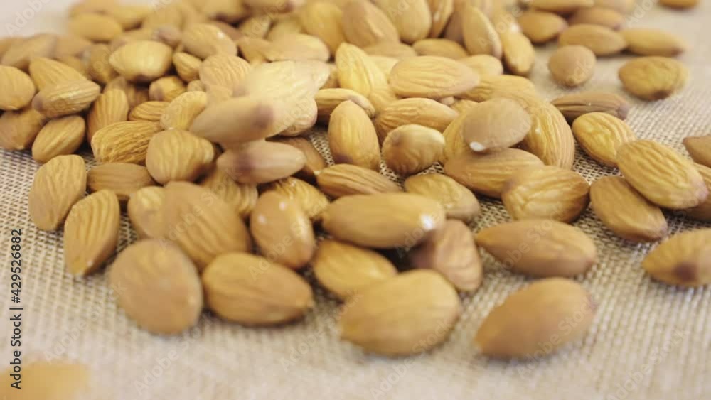 Close up almonds seed rotate on brown fabric, Slow motion almond kernels rotation with brick background, Front view almond nuts rotating, Concept whole grains of food for healthy. Close up almonds seed rotate on brown fabric, Slow motion almond kernels rotation with brick background, Front view almond nuts rotating, Concept whole grains of food for healthy.