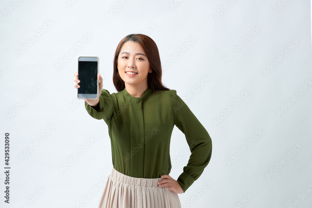 Young beautiful woman in casual style holding phone looking at camera and showing phone display. Young beautiful woman in casual style holding phone looking at camera and showing phone display.