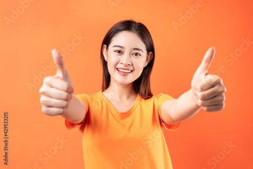 Image of young Asian woman wearing orange t-shirt on orange background © Timeimage