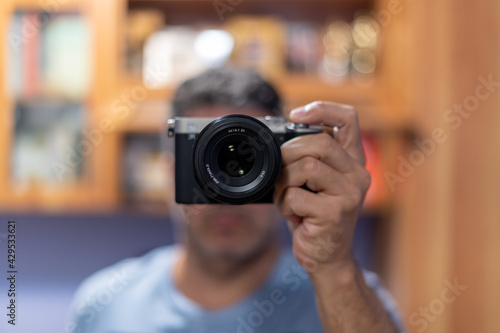 Homem segurando sua camera fotografica e fazendo auto-retrato em frente ao espelho