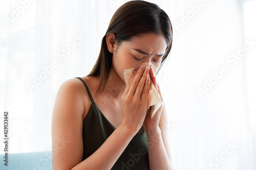 Image of young Asian woman sneezing