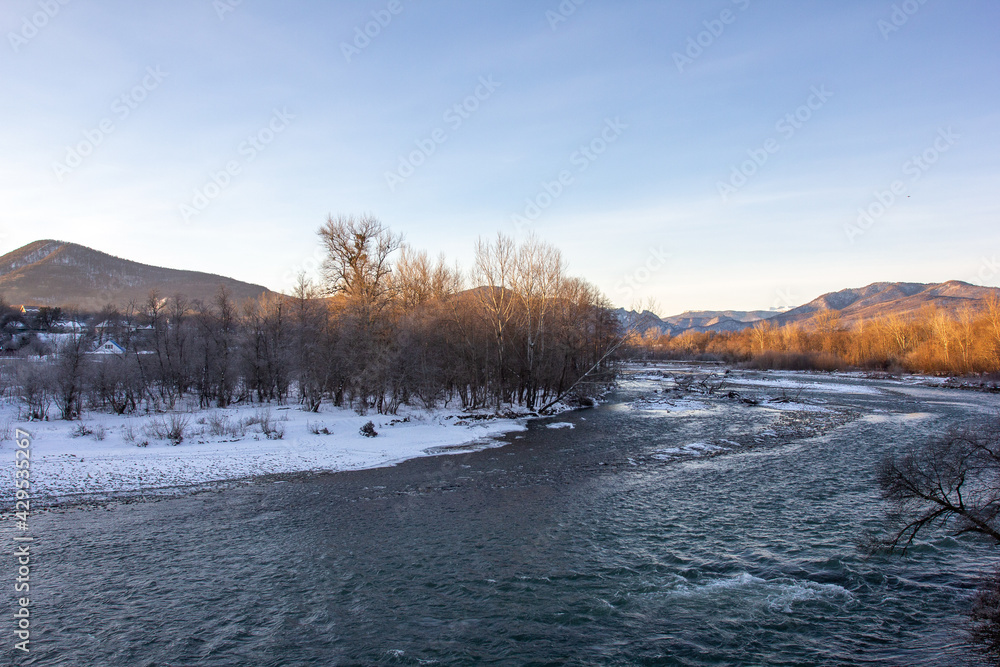 Winter in the foothills, an ice-free river on a frosty morning in the rays of the rising sun. Winter in the foothills, an ice-free river on a frosty morning in the rays of the rising sun.