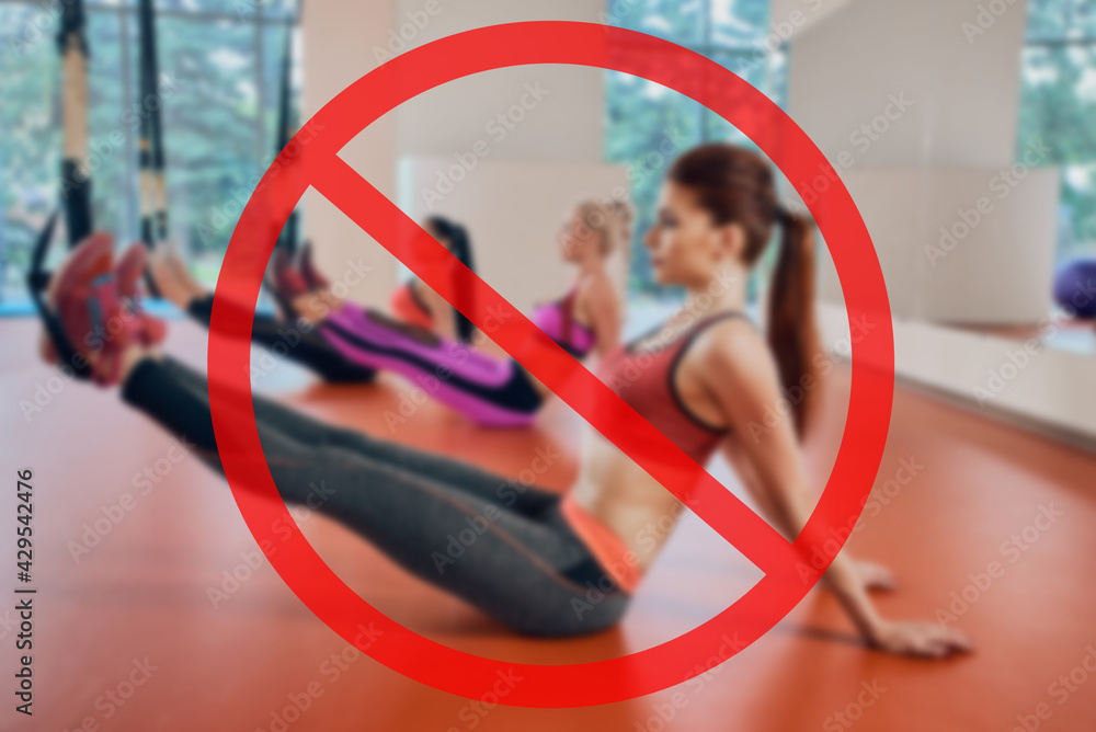 gym ban due to sanitary measures. Young attractive women do suspension training with fitness straps in the gym's studio