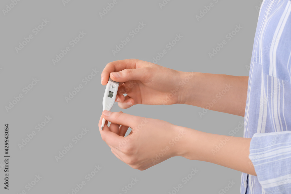 Woman with electronic thermometer on grey background, closeup Woman with electronic thermometer on grey background, closeup