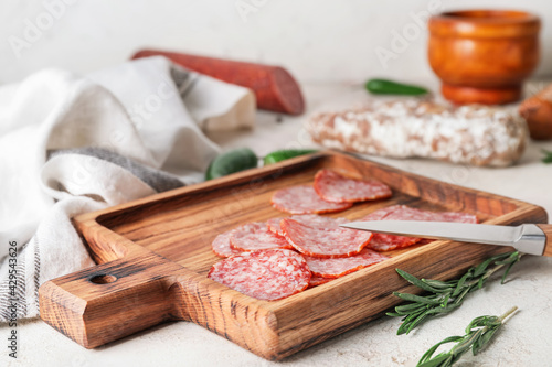 Board with slices of salami on table