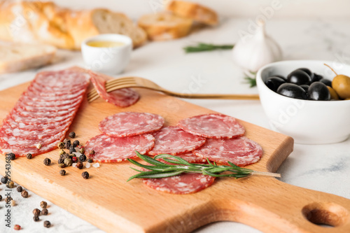 Board with tasty salami on table