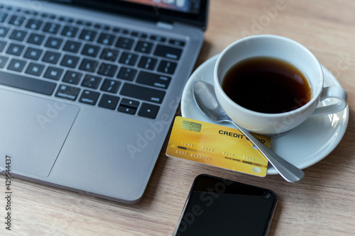 Credit card of laptop computer,smartphone and coffee cup on wooden background,Online banking Concept