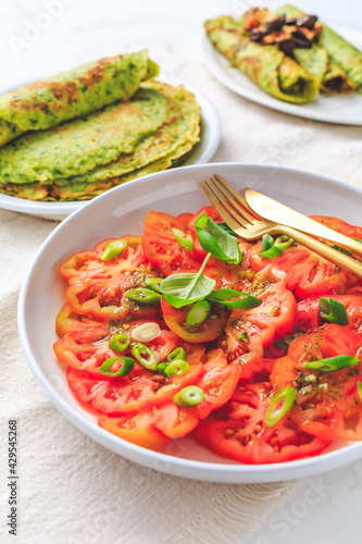 Tomato salad with onions and ramson pancakes or crepes