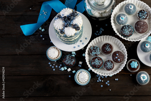 Fototapeta Naklejka Na Ścianę i Meble -  Delicious cake and cupcakes in blue on wooden background. Table setting for celebration.