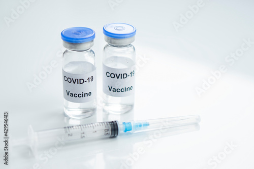 Two Vial of Covid-19 vaccine with syringe on white glass medical background