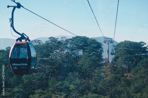 Circulating cable car between Dalat bus station and Robin Hill Truc Lam Vietnam. Intermediate support tower. Picturesque landscape view. High Pine forest tree tops, mountain, clear sky. Collection
