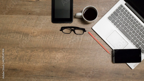 Notebook, coffee cup, glasses, pencil, on a wooden background.	