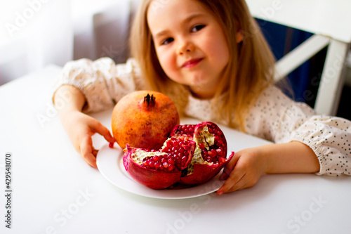 Little girl holding a pomegranate. Symbol of the Jewish New Year. Rosh ha Shana. Healthy organic sweet fruits. 