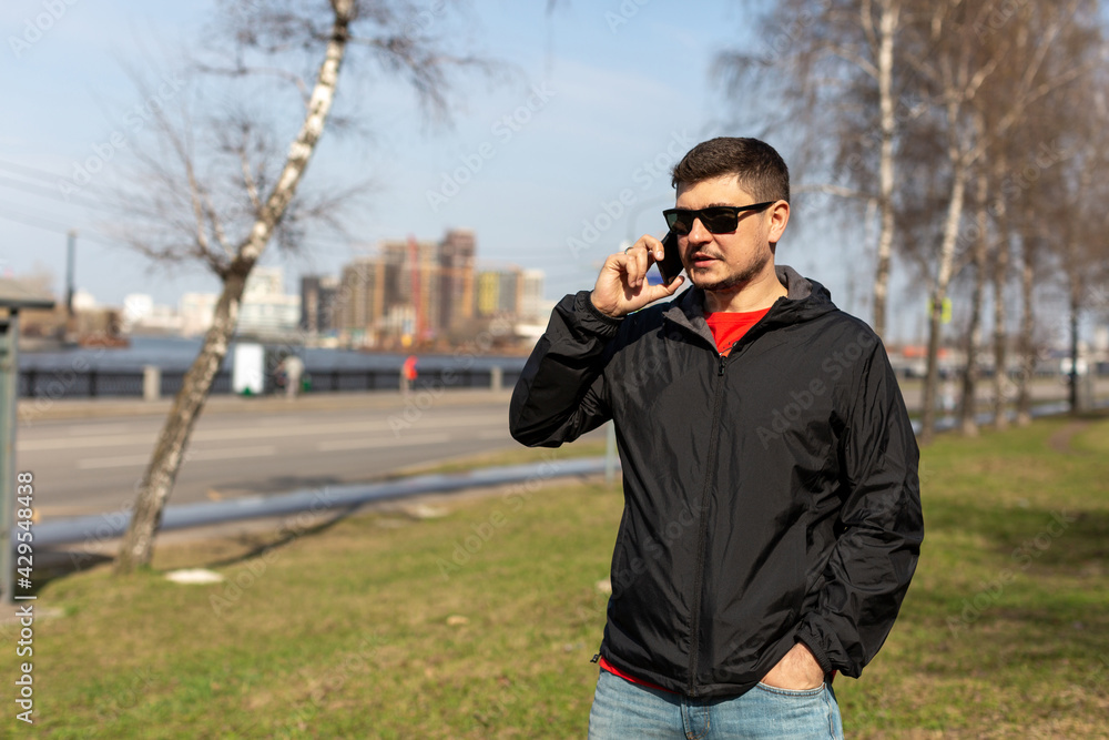 A man in sunglasses stands on the street of the city and talks on the phone A man in sunglasses stands on the street of the city and talks on the phone