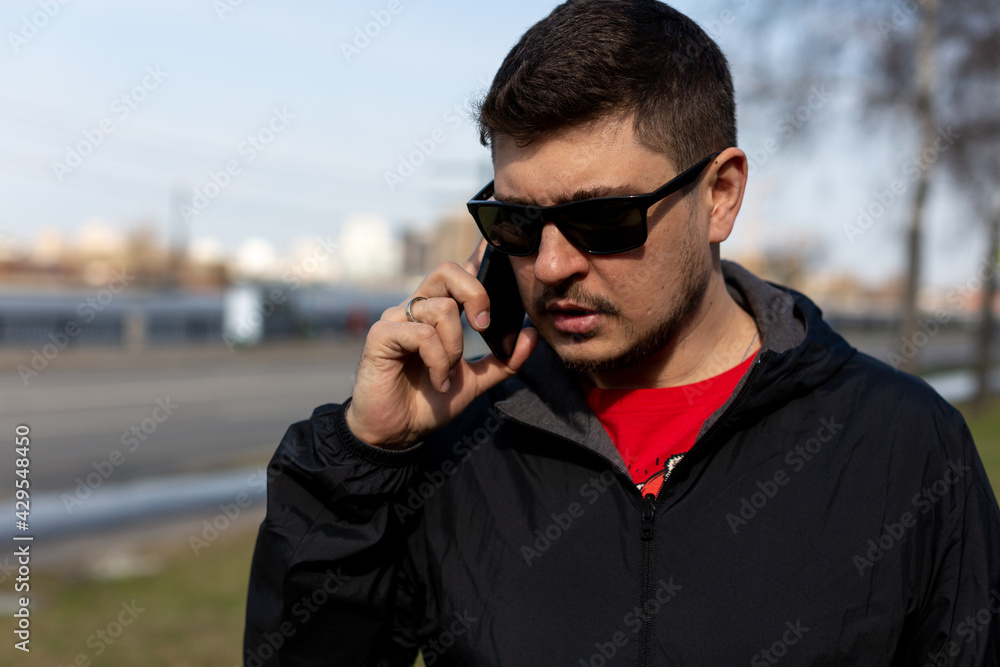 A man in sunglasses stands on the street of the city and talks on the phone A man in sunglasses stands on the street of the city and talks on the phone