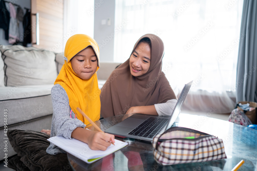 asian muslim mother help her daughter to learn online using laptop studying from home asian muslim mother help her daughter to learn online using laptop studying from home