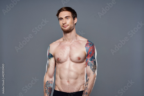 sporty man with a naked torso pumped up press tattoos on his arms