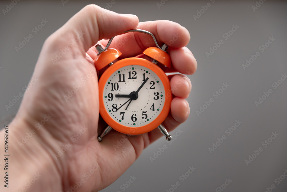 Caucasian white man hands holding a small orange alarm clock in the palm. Concept of time. Caucasian white man hands holding a small orange alarm clock in the palm. Concept of time.