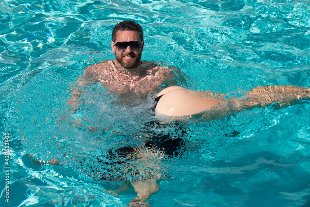 Life winner. Sexy couple in pool. Summer resort. Buttocks in bikini. Summertime vacation.