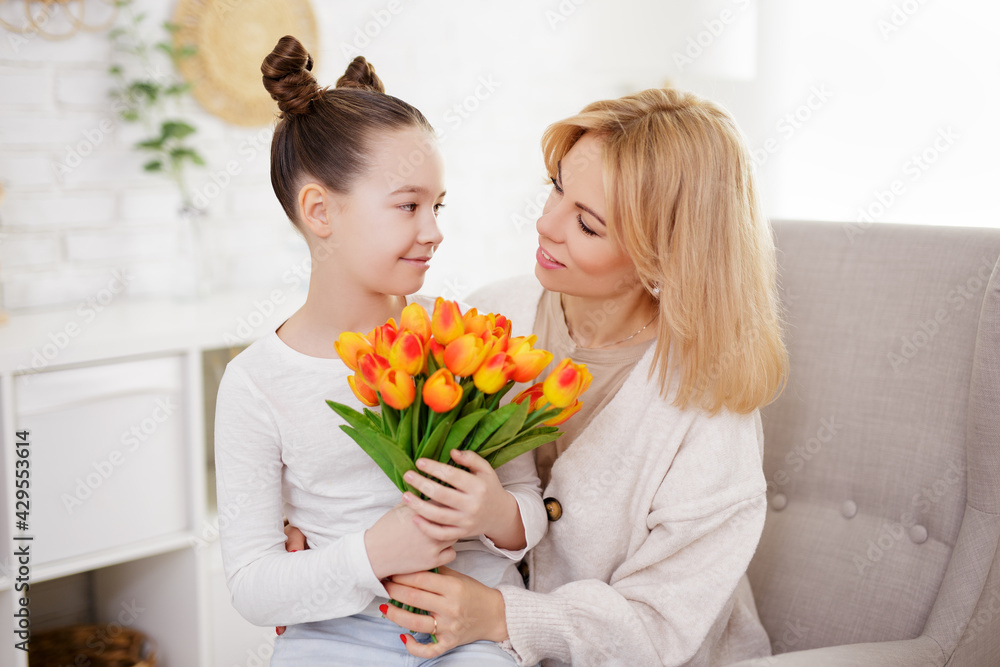 family and mother's day concept - cute girl giving flowers to her mother in living room family and mother's day concept - cute girl giving flowers to her mother in living room