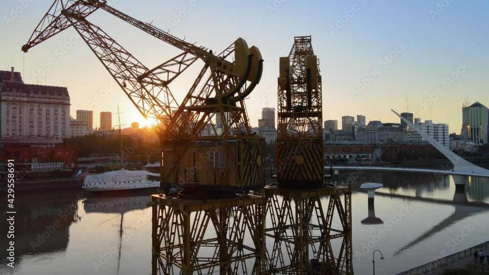 Aerial orbit right shot of two old port cranes in Puerto Madero docks at sunset Aerial orbit right shot of two old port cranes in Puerto Madero docks at sunset