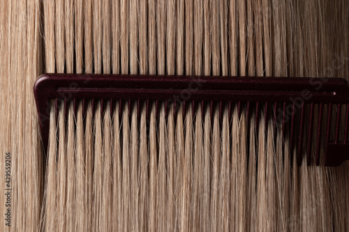 Combing straight blonde smooth hair close-up. Comb, strands, care, hairstyle, styling, healthy hair, botox, salon, hairdresser