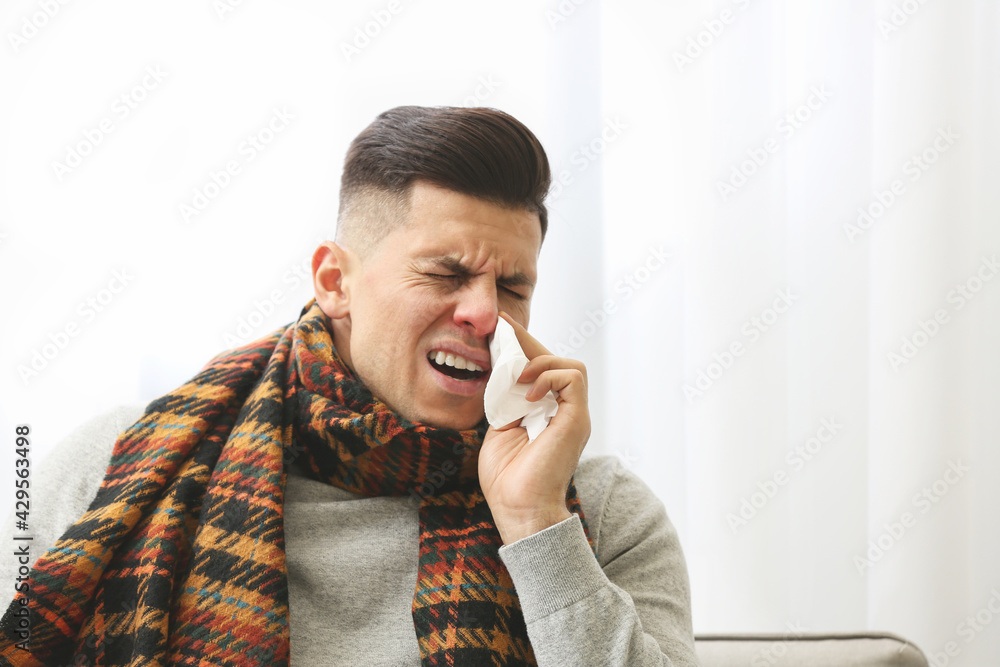 Ill man with scarf suffering from head cold at home Ill man with scarf suffering from head cold at home