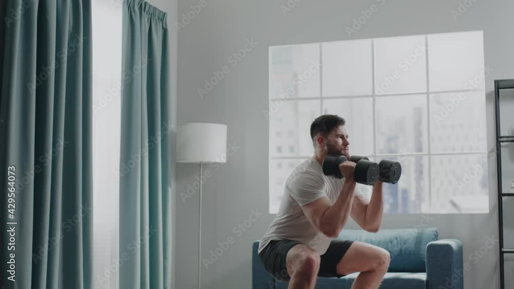 Fitness trainer performs squats holding dumbbells in hands Fitness trainer performs squats holding dumbbells in hands