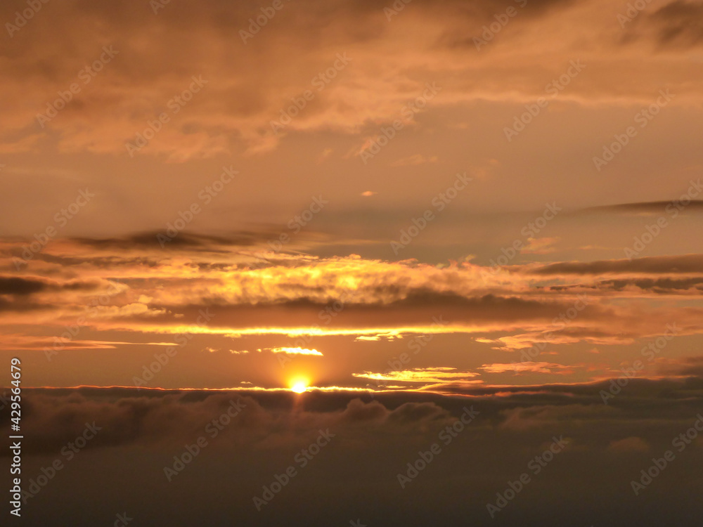 Colofrul sunrise seen from a small hill in the suburbs of Xilinhot, Inner Mongolia. The sky is painted in orange, red and pink. Soft colors of sunrise. The sun is surrounded by thick clouds. Daybreak