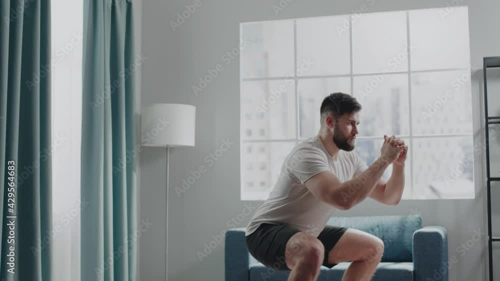 Active athlete guy warms up performing bodyweight squats Active athlete guy warms up performing bodyweight squats