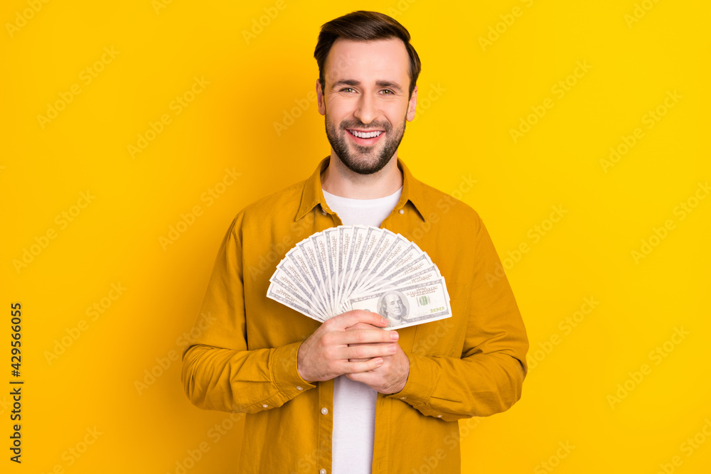Photo of confident cheerful young gentleman dressed casual outfit holding money fan smiling isolated yellow color background Photo of confident cheerful young gentleman dressed casual outfit holding money fan smiling isolated yellow color background