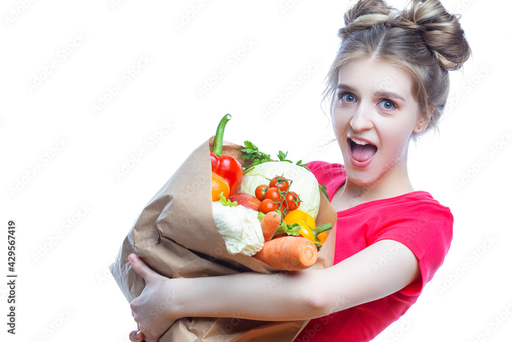 Young Caucasian Female Holding Eco Paper Bag Filled With Multiple Vegetables and Groceries Posing Against White Background. Young Caucasian Female Holding Eco Paper Bag Filled With Multiple Vegetables and Groceries Posing Against White Background.