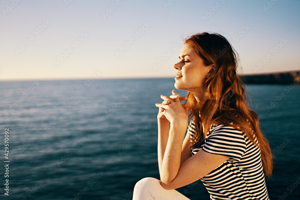 traveler at sunset sitting on a stone near the sea portrait side view traveler at sunset sitting on a stone near the sea portrait side view